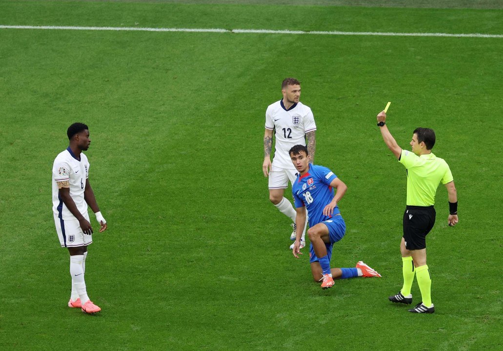 El árbitro Umut Meler (d) muestra amarilla al defensa Marc Guehi durante el partido de octavos de final que han jugado Inglaterra y Eslovaquia en Gelsenkirchen, Alemania. EFE/EPA/GEORGI LICOVSKI